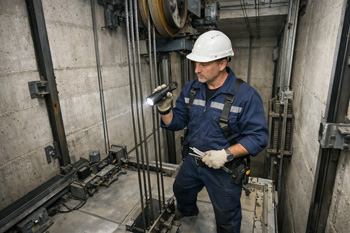 سرویس‌کار آسانسور در حال بررسی ایمنی سیم‌بکسل‌ها داخل چاه