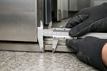 اندازه‌گیری فاصله بین کابین و طبقه توسط بازرس برای جلوگیری از رد شدن استاندارد آسانسور